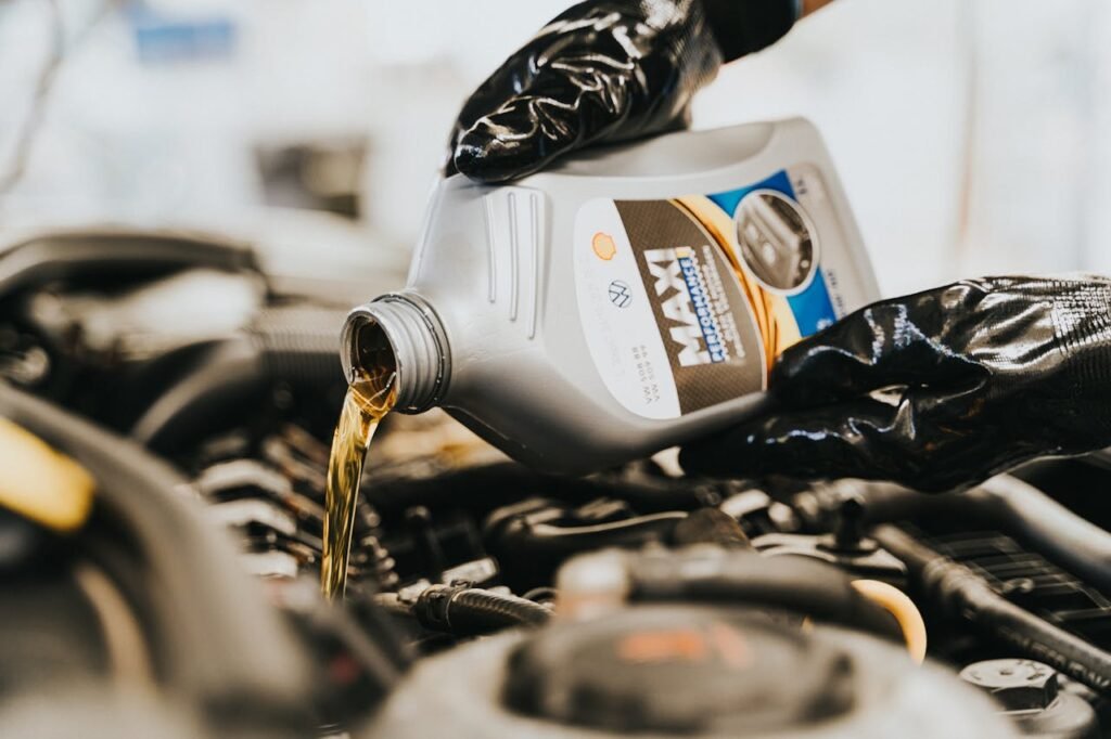 close-up-of-pouring-oil-to-engine-13065697 Close-up of a mechanic pouring engine oil into a car engine, highlighting maintenance work.